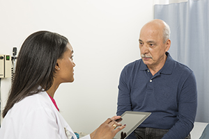 Man talking with health care provider in exam room.