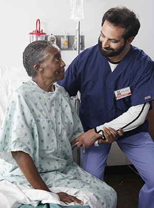 Healthcare provider helping woman out of hospital bed.